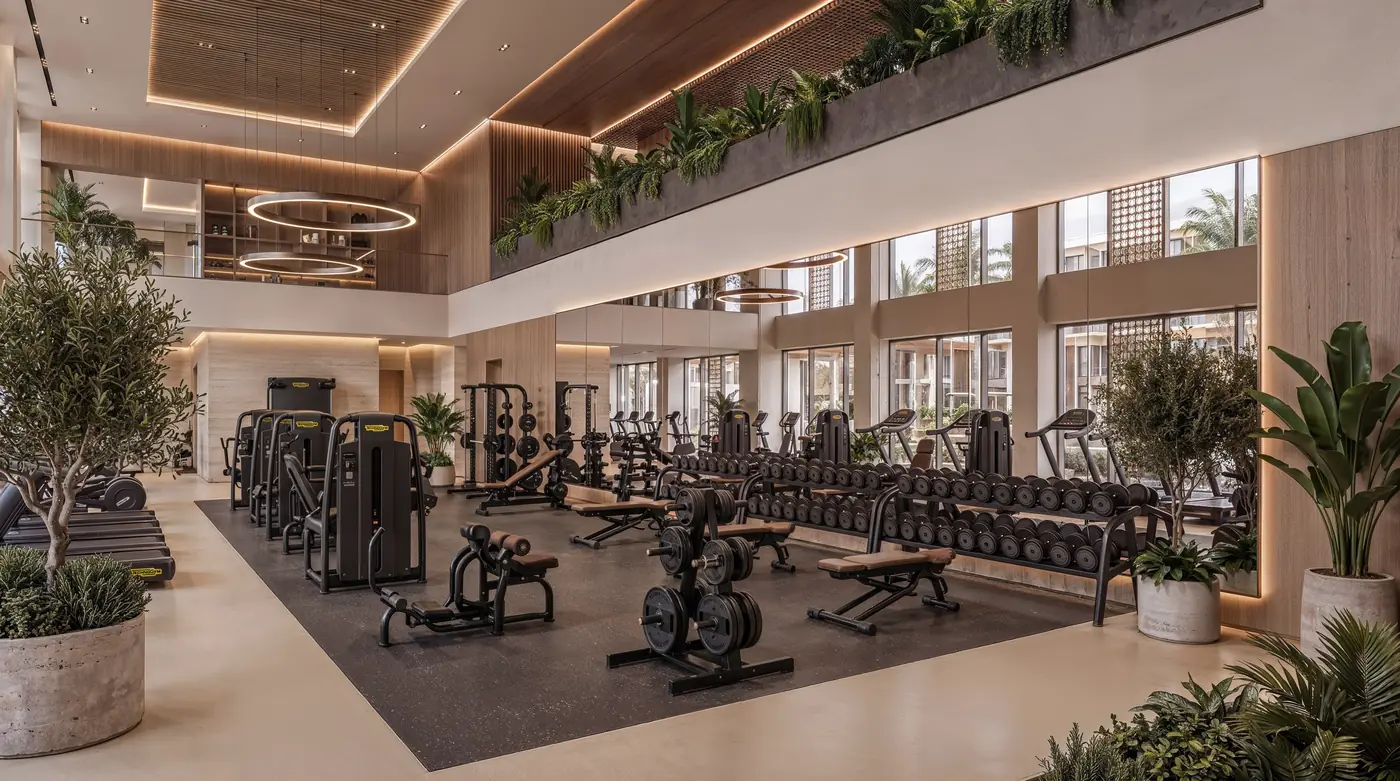 Double-height residents' gym at Mira Ocean Estates with cardio and strength equipment overlooking the gardens